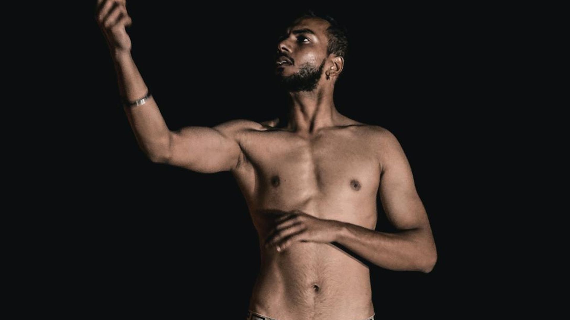 Man performing a controlled strength exercise in a minimalist dark room.